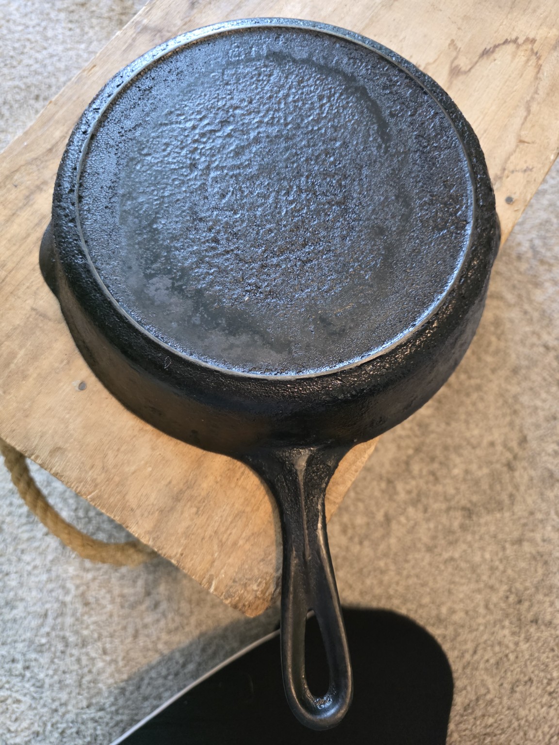 Carbon-covered underside of a vintage skillet with a partly hidden maker's mark